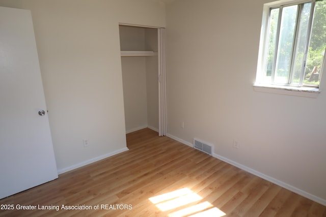 3700-3702 Malibu Dr, Lansing, MI 48911 - unfurnished bedroom featuring multiple windows, wood finished floors, and a closet