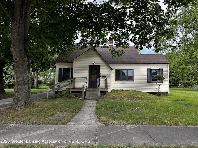1115 Rose Ave, Big Rapids, MI 49307 - view of front of house with a shingled roof, a front yard, and a chimney