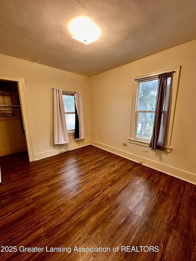 1115 Rose Ave, Big Rapids, MI 49307 - unfurnished bedroom with dark wood-style floors, multiple windows, and a closet
