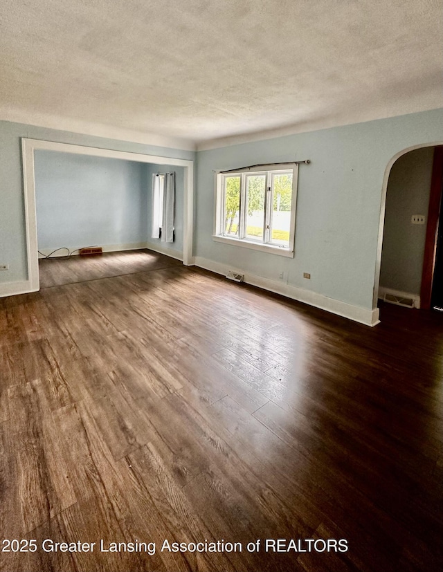 1115 Rose Ave, Big Rapids, MI 49307 - empty room featuring arched walkways, dark wood-style floors, and a textured ceiling