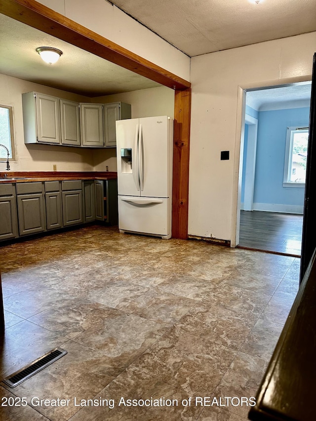 1115 Rose Ave, Big Rapids, MI 49307 - kitchen featuring white fridge with ice dispenser, gray cabinetry, and dark countertops
