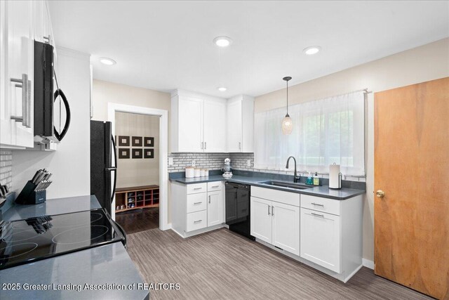 1395 Biscayne Way, Haslett, MI 48840 - kitchen with black appliances, light wood-type flooring, white cabinetry, backsplash, and dark countertops