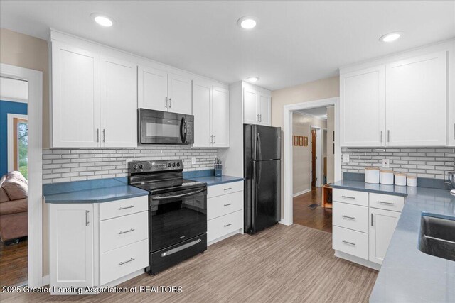 1395 Biscayne Way, Haslett, MI 48840 - kitchen featuring black appliances, light wood-type flooring, white cabinetry, and recessed lighting