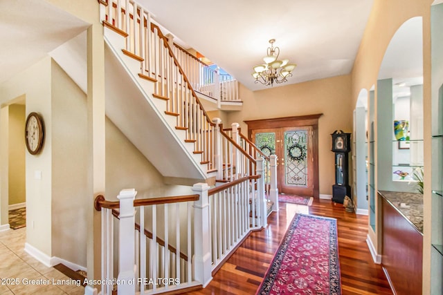 10696 W Clark Rd, Eagle, MI 48822 - entrance foyer featuring wood finished floors, a chandelier, arched walkways, and stairs