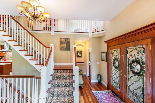 10696 W Clark Rd, Eagle, MI 48822 - foyer featuring wood finished floors, a chandelier, stairway, arched walkways, and a towering ceiling