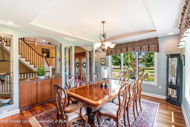 10696 W Clark Rd, Eagle, MI 48822 - dining space with a raised ceiling, a chandelier, arched walkways, stairway, and wood finished floors