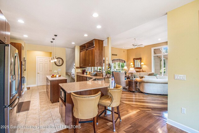 10696 W Clark Rd, Eagle, MI 48822 - kitchen featuring stainless steel fridge with ice dispenser, a center island, a peninsula, ceiling fan, and brown cabinets