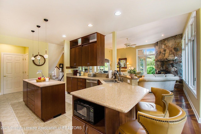 10696 W Clark Rd, Eagle, MI 48822 - kitchen with black microwave, dishwasher, an island with sink, a ceiling fan, and light stone counters