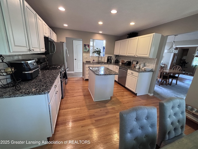 2665 Allium Dr, Holt, MI 48842 - kitchen with stainless steel appliances, backsplash, a kitchen island, white cabinets, and recessed lighting