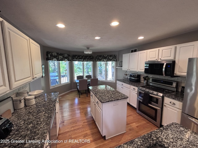 2665 Allium Dr, Holt, MI 48842 - kitchen with appliances with stainless steel finishes, light wood finished floors, white cabinets, a kitchen island, and recessed lighting