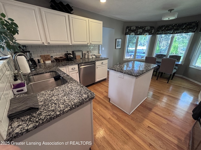 2665 Allium Dr, Holt, MI 48842 - kitchen with stainless steel dishwasher, light wood-style floors, tasteful backsplash, a center island, and white cabinetry
