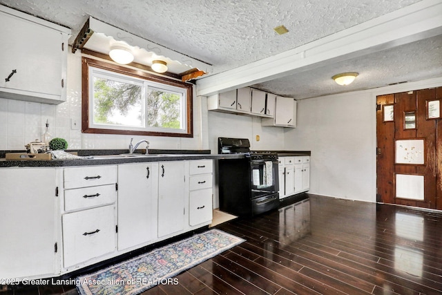321 Lamb St, Perry, MI 48872 - kitchen featuring black range with gas stovetop, dark countertops, white cabinetry, dark wood-style floors, and a textured ceiling