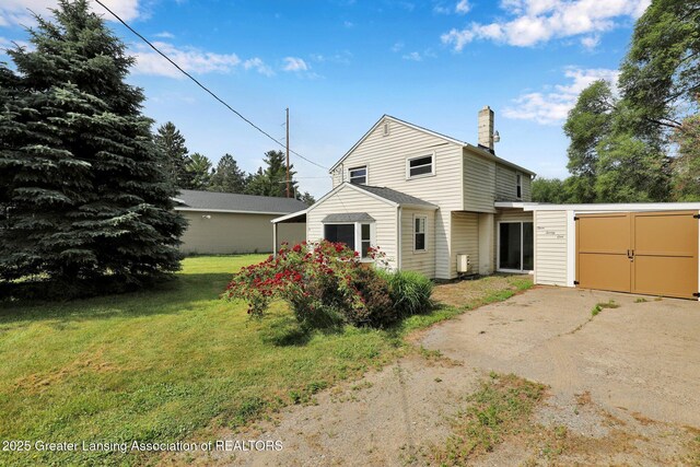 321 Lamb St, Perry, MI 48872 - rear view of house featuring a chimney, a yard, driveway, and an attached garage