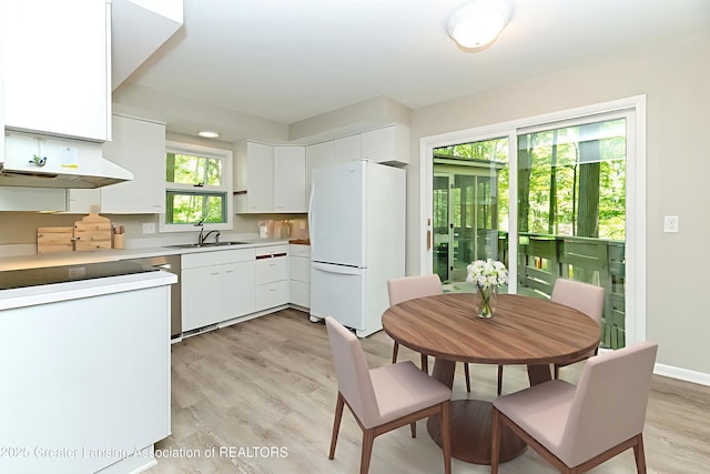 13368 Forest Hill Rd, Grand Ledge, MI 48837 - kitchen featuring freestanding refrigerator, white cabinets, light wood-type flooring, under cabinet range hood, and light countertops