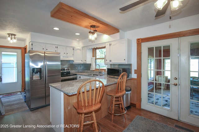 10996 Benton Rd, Grand Ledge, MI 48837 - kitchen featuring stainless steel appliances, under cabinet range hood, a peninsula, white cabinetry, and dark wood finished floors
