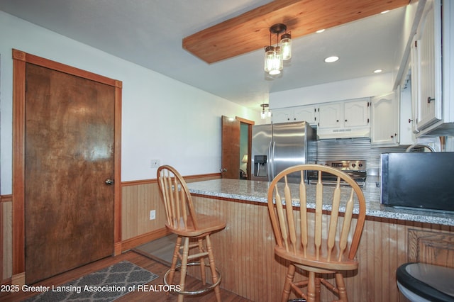 10996 Benton Rd, Grand Ledge, MI 48837 - kitchen featuring appliances with stainless steel finishes, wood finished floors, white cabinets, a peninsula, and under cabinet range hood