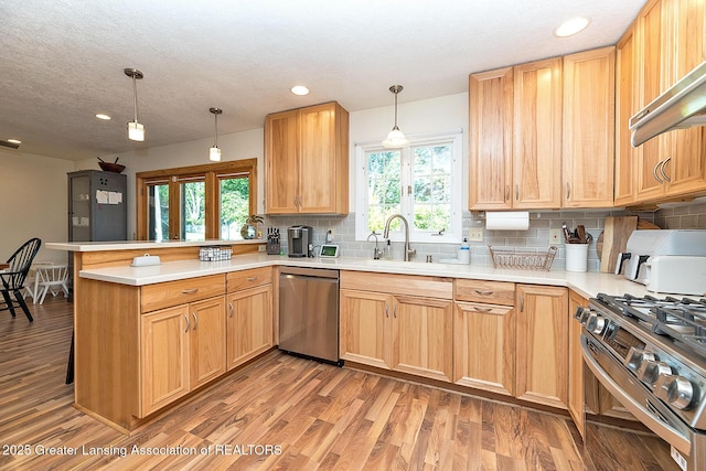 3855 Sandlewood Dr, Okemos, MI 48864 - kitchen with appliances with stainless steel finishes, a peninsula, decorative backsplash, healthy amount of natural light, and recessed lighting