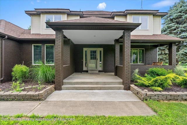 527 Day Rd, Owosso, MI 48867 - view of exterior entry with brick siding, covered porch, and a shingled roof