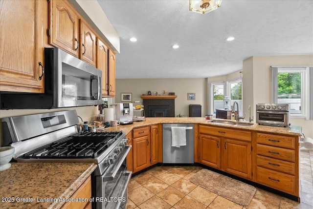 527 Day Rd, Owosso, MI 48867 - kitchen featuring stainless steel appliances, recessed lighting, a fireplace, brown cabinets, and a peninsula