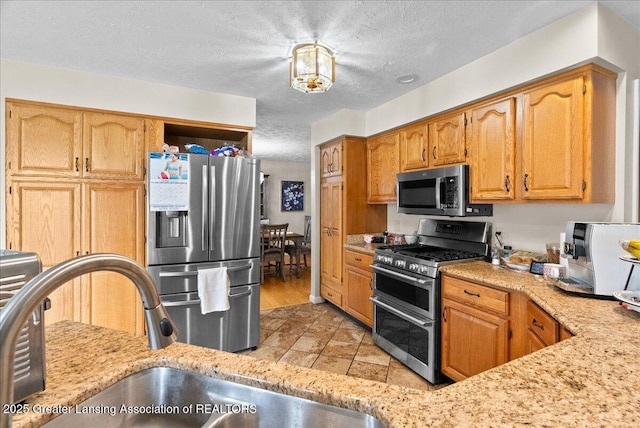 527 Day Rd, Owosso, MI 48867 - kitchen featuring stainless steel appliances, a textured ceiling, and light stone countertops