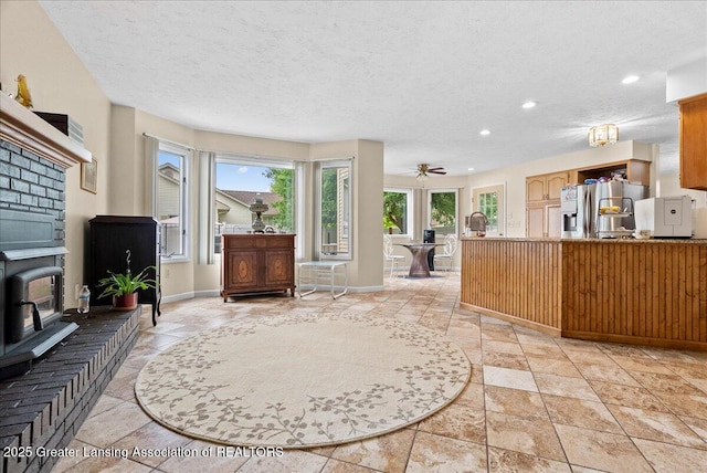 527 Day Rd, Owosso, MI 48867 - living area with recessed lighting, a wood stove, stone tile flooring, a textured ceiling, and a ceiling fan
