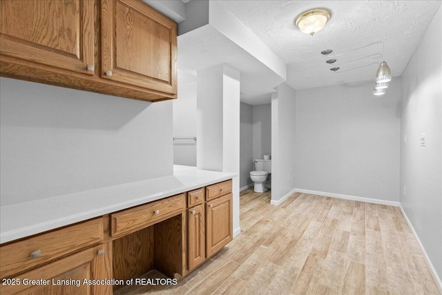 527 Day Rd, Owosso, MI 48867 - kitchen with light wood-type flooring, light countertops, brown cabinetry, and a textured ceiling