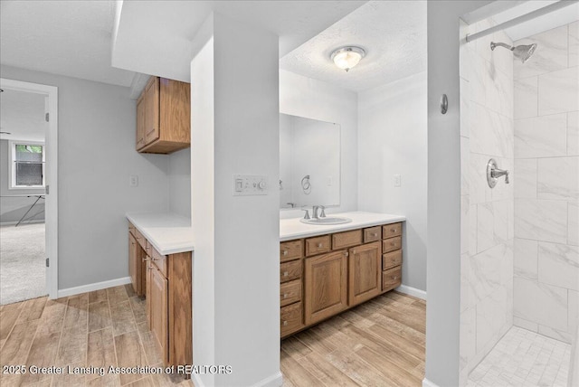 527 Day Rd, Owosso, MI 48867 - bathroom with wood finished floors, vanity, tiled shower, and a textured ceiling