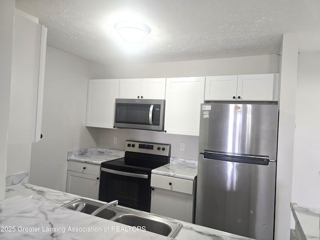 12907 Townsend Dr Unit 612, Grand Ledge, MI 48837 - kitchen featuring appliances with stainless steel finishes, white cabinets, a textured ceiling, and light stone countertops