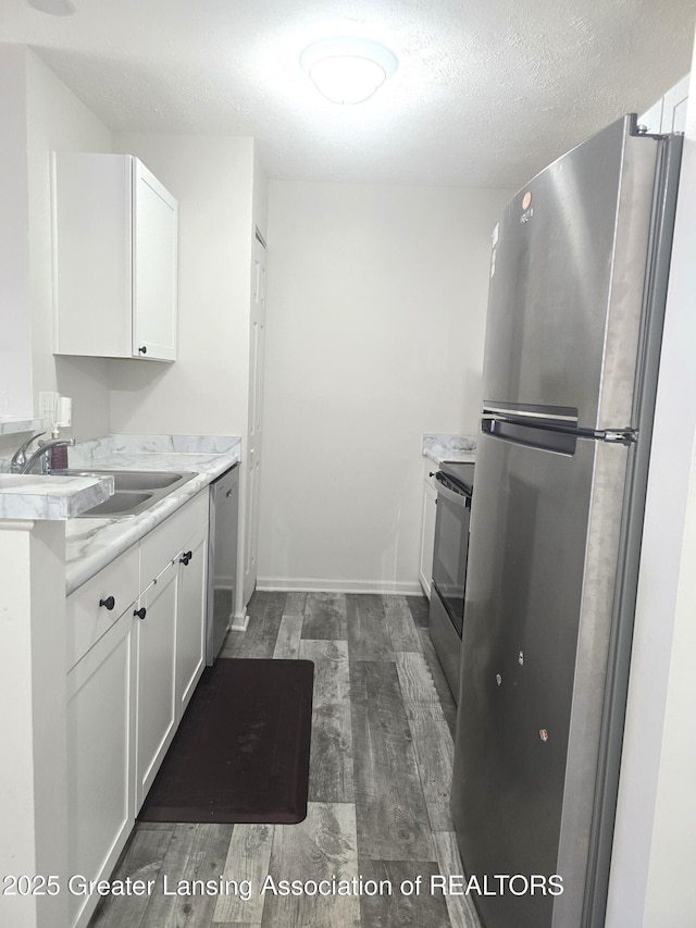 12907 Townsend Dr Unit 612, Grand Ledge, MI 48837 - kitchen with stainless steel appliances, white cabinetry, light countertops, dark wood finished floors, and a textured ceiling