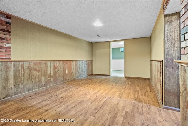 2218 Coolridge Rd, Holt, MI 48842 - spare room with wood finished floors, a textured ceiling, and a wainscoted wall