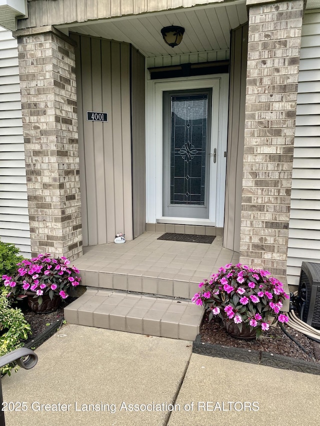 4001 Canyon Cv # 56, Holt, MI 48842 - doorway to property featuring brick siding and covered porch