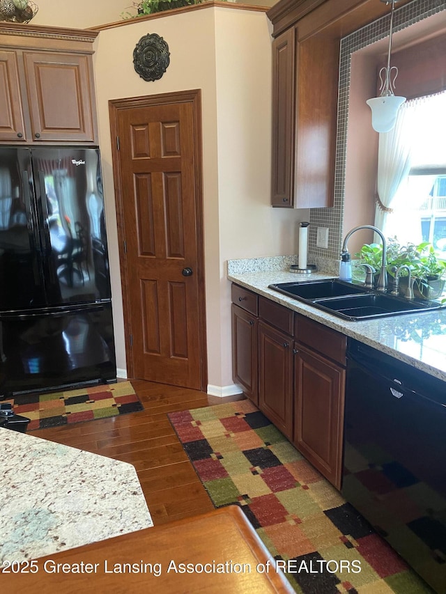 4001 Canyon Cv # 56, Holt, MI 48842 - kitchen featuring black appliances, light wood-type flooring, decorative light fixtures, and light stone counters