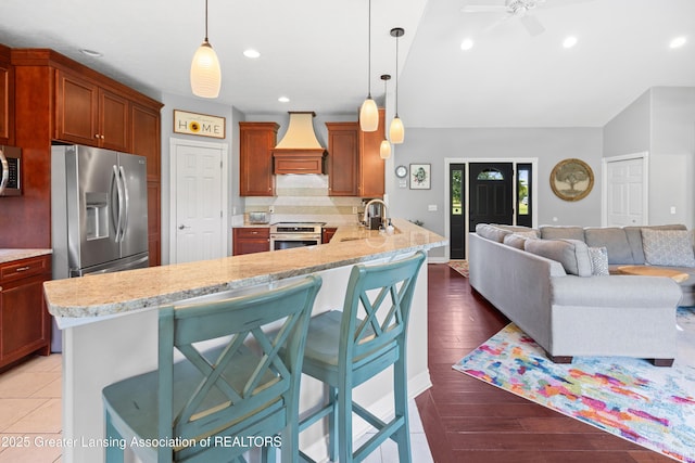 14747 Forest Hill Rd, Grand Ledge, MI 48837 - kitchen featuring stainless steel appliances, premium range hood, decorative backsplash, open floor plan, and light stone counters