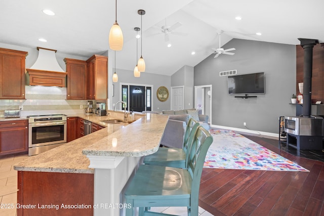 14747 Forest Hill Rd, Grand Ledge, MI 48837 - kitchen featuring stainless steel appliances, ceiling fan, custom exhaust hood, a wood stove, and a peninsula