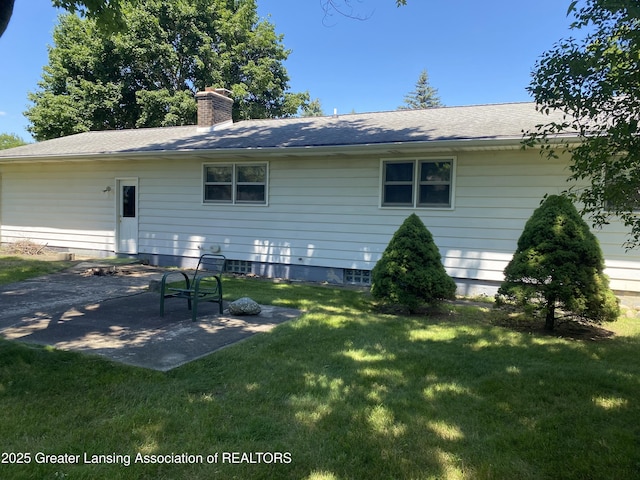 3931 Berry Ridge Dr, Holt, MI 48842 - rear view of house with a chimney, a patio area, a lawn, and roof with shingles