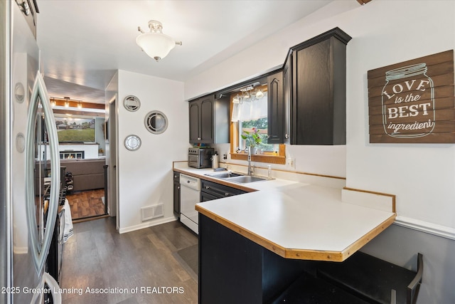 8713 Wintergreen St, Lansing, MI 48917 - kitchen featuring freestanding refrigerator, a peninsula, dark wood-type flooring, light countertops, and dishwasher