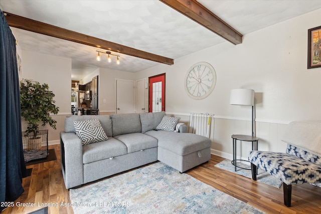 8713 Wintergreen St, Lansing, MI 48917 - living room featuring beamed ceiling, wood finished floors, and a wainscoted wall
