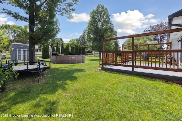 8713 Wintergreen St, Lansing, MI 48917 - view of green lawn featuring a storage unit, a wooden deck, and an outdoor pool