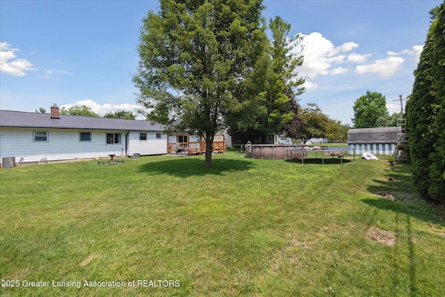 8713 Wintergreen St, Lansing, MI 48917 - view of grassy yard with a trampoline and a deck