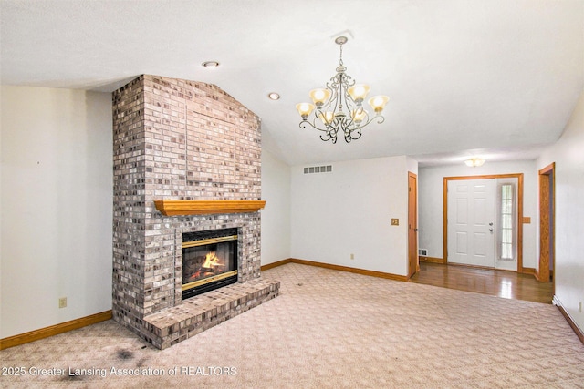 6875 W Howe Rd, Dewitt, MI 48820 - unfurnished living room featuring carpet flooring, lofted ceiling, a chandelier, and a brick fireplace