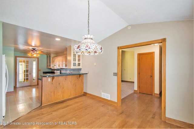 6875 W Howe Rd, Dewitt, MI 48820 - kitchen with dark countertops, a breakfast bar area, glass insert cabinets, a peninsula, and pendant lighting