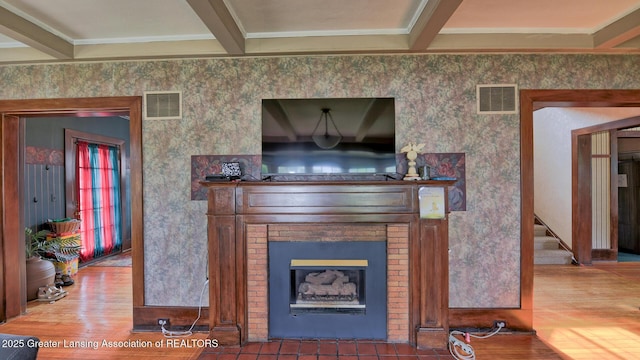502 S Main St, Eaton Rapids, MI 48827 - living room featuring wood finished floors, crown molding, a fireplace, stairway, and wallpapered walls