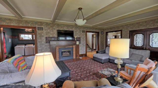 502 S Main St, Eaton Rapids, MI 48827 - living area featuring washer and dryer, wallpapered walls, beamed ceiling, a fireplace, and ornamental molding