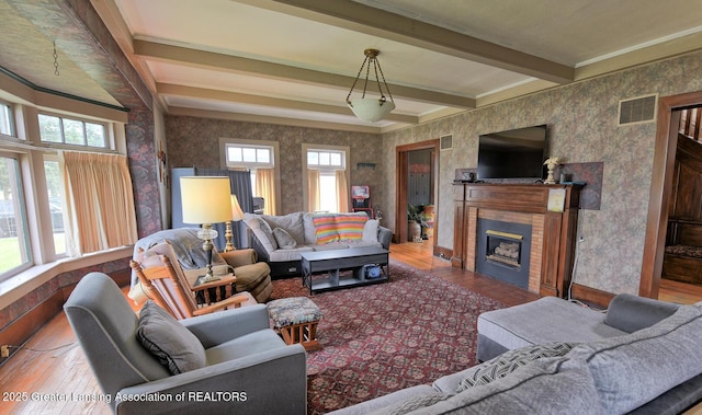 502 S Main St, Eaton Rapids, MI 48827 - living area featuring wallpapered walls, wood finished floors, beam ceiling, a fireplace, and crown molding