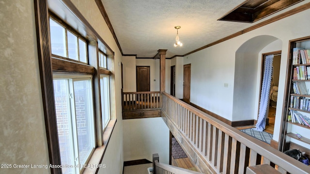 502 S Main St, Eaton Rapids, MI 48827 - hallway featuring arched walkways, ornamental molding, a textured ceiling, and an upstairs landing