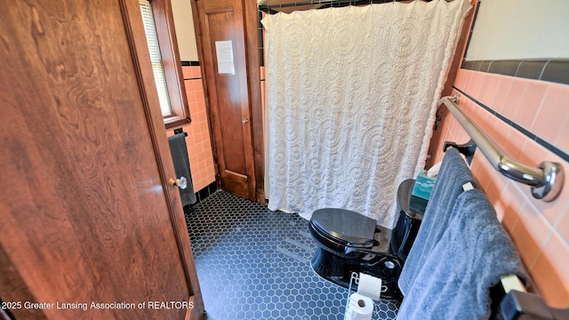 502 S Main St, Eaton Rapids, MI 48827 - bathroom with tile walls, tile patterned floors, curtained shower, and a wainscoted wall