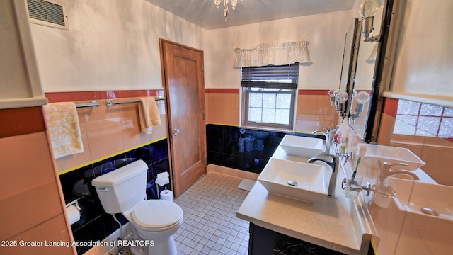 502 S Main St, Eaton Rapids, MI 48827 - bathroom with tile walls, tile patterned flooring, double vanity, and wainscoting