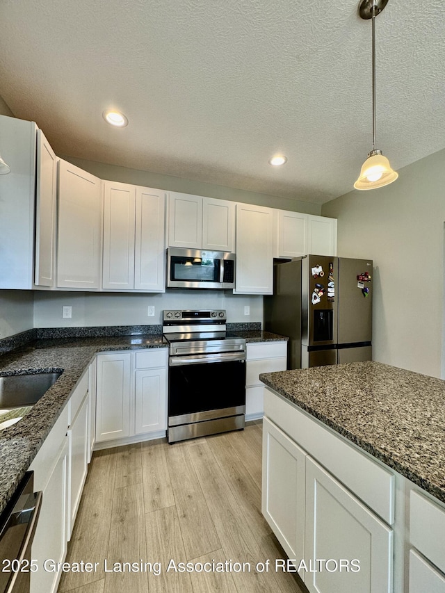 4314 Ringneck Ln, Holt, MI 48842 - kitchen with stainless steel appliances, light wood-type flooring, white cabinetry, recessed lighting, and hanging light fixtures