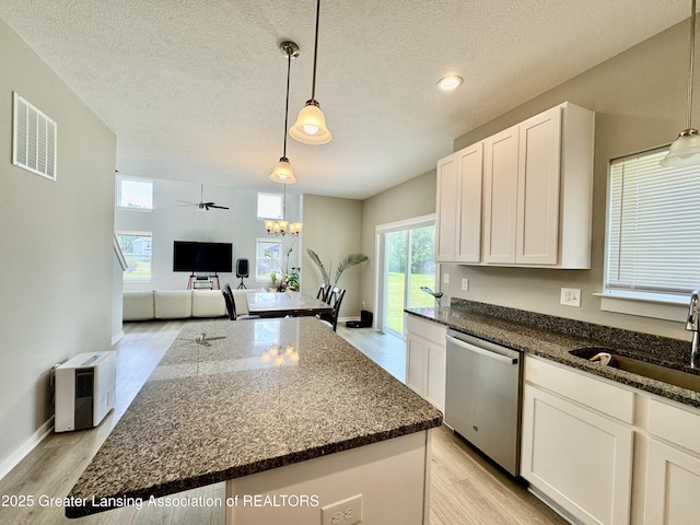 4314 Ringneck Ln, Holt, MI 48842 - kitchen with stainless steel dishwasher, light wood-type flooring, white cabinetry, dark stone counters, and a textured ceiling