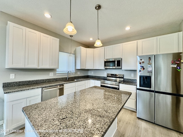 4314 Ringneck Ln, Holt, MI 48842 - kitchen with stainless steel appliances, white cabinetry, light wood-style floors, a kitchen island, and recessed lighting